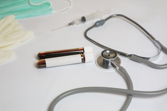 hands of a lab technician with a tube of blood sample and a rack with other samples / lab technician holding blood tube sample for study