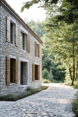 Obraz premium Stone house with wooden shutters set in a tranquil wooded area during the early morning light, featuring a winding cobblestone path leading through lush greenery