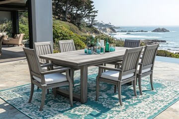 Obraz premium Outdoor dining set with rectangular table and six chairs, crafted from wood with weathered gray finish, placed on blue-green and white area rug, beach view backdrop.