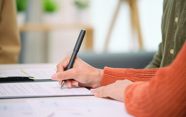 Asian couple reviewing and sign contract financial documents with the guidance of  advisor at...