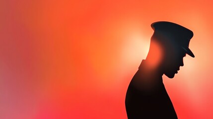 A silhouette of a police officer against a vibrant orange backdrop, conveying emotion and reflection.