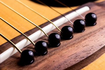 A six-string guitar bridge with gold strings. taken in close-up in dark colors with space for text