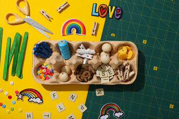 Art supplies in egg tray on yellow background, top view