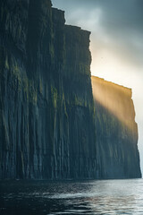 Dramatic cliffs with sunlight illuminating the ocean at dawn on a calm day