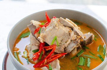 Spicy pork bone soup in a bowl with red chili and fresh herbs, perfect for Asian cuisine.