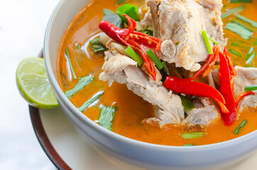 Spicy pork bone soup in a bowl with red chili and fresh herbs, perfect for Asian cuisine.