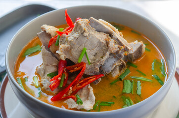 Spicy pork bone soup in a bowl with red chili and fresh herbs, perfect for Asian cuisine.