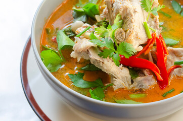 Spicy pork bone soup in a bowl with red chili and fresh herbs, perfect for Asian cuisine.