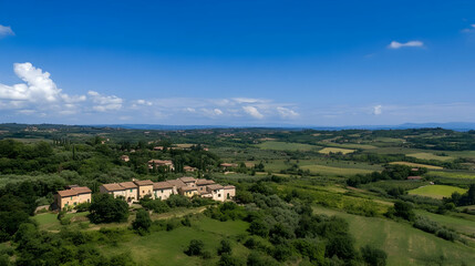 Fototapeta premium Aerial view of idyllic Tuscan countryside village, rolling hills, and clear blue sky; perfect for travel brochures