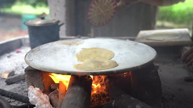 Latin american woman making traditional tortillas on a comal