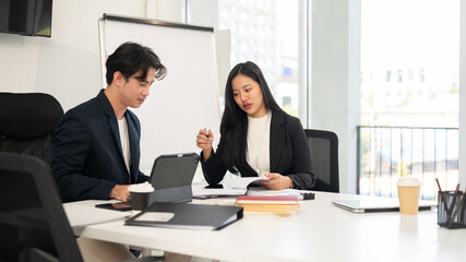 Two smart and professional Asian businesspeople are meeting in a meeting room, planning a project.