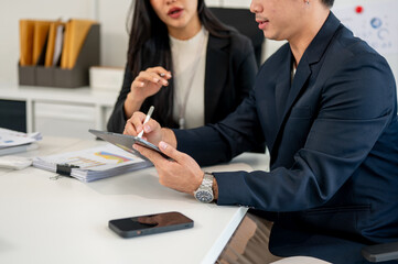 A businessman using the tablet during a meeting with his team in the meeting room.