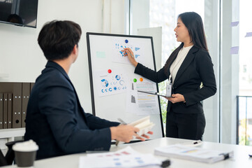 A focused and confident Asian businesswoman explains her project to everyone in the meeting.