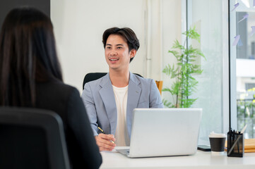 A confident and friendly Asian businessman or CEO is interviewing a female candidate in his office.