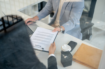 A close-up of a female candidate handing her resume to a CEO during an interview in the office.