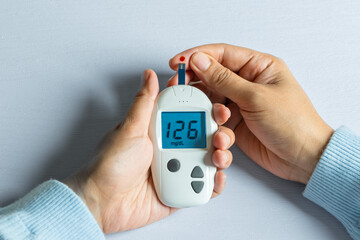 Woman's hands checking diabetes and hyperglycemia with digital blood sugar meter. Healthcare and medical concept	