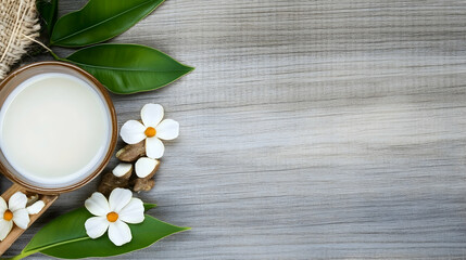 Creamy beverage with flowers and leaves on wooden background; wellness, spa, or health concept