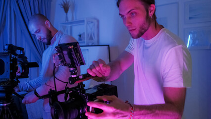 Videographer work. Cameraman set. Man looks at display professional studio filming device....