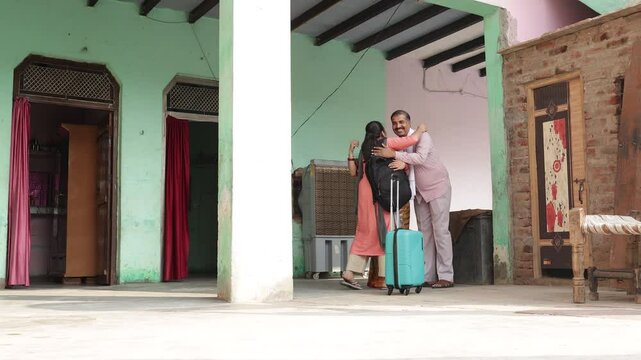Happy rural indian parents waving hand say goodbye to young daughter with trolley bag going out for education and further studies. 4k