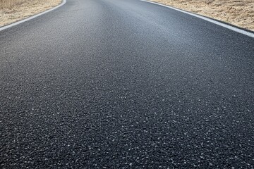 Asphalt road curving gently, showing texture and lines.