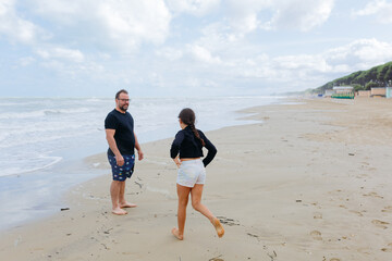 dad and daughter standing on the sand beach next to the sea