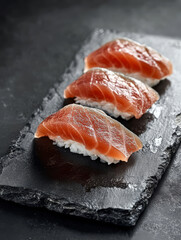 Fresh salmon nigiri served on a black slate platter in a modern dining setting