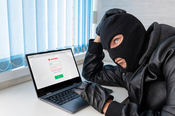 Theft of personal data. Hacking site. A bandit in the office picks up a password to log in on a...