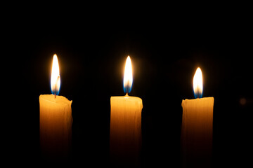 orange candle burns in the dark on a black background. The concept of memory and sorrow.