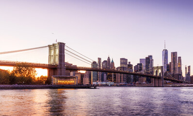 Naklejka premium A panoramic sunset view of the Brooklyn Bridge stretching towards Manhattan