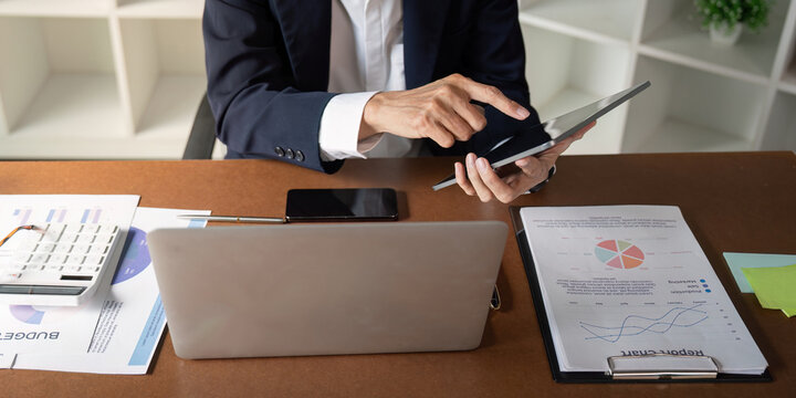 Senior financial analyst utilizing tablet to enhance report analysis in a modern office environment