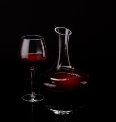Elegant presentation of red wine in a glass and a decanter against a dark background