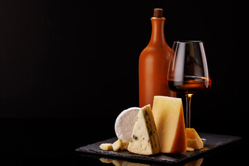 A refined selection of aged cheeses presented on a board, accompanied by a glass of wine