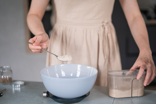 Girl in a beige dress pours flour into a bowl closeup