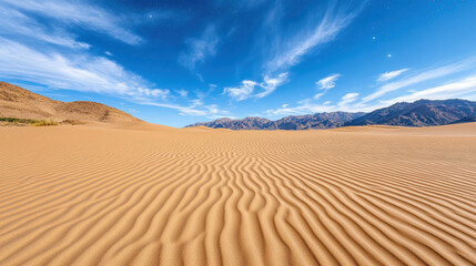 Naklejka premium Breathtaking sand dunes under clear blue sky with distant mountains