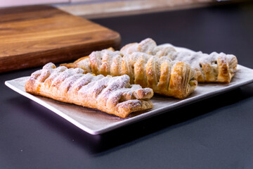 Delicious homemade cakes. Puff pastry with cherries, generously sprinkled with icing sugar on top. Delicious fresh buns close up view