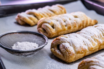 Delicious homemade cakes. Puff pastry with cherries, generously sprinkled with icing sugar on top. Delicious fresh buns close up view