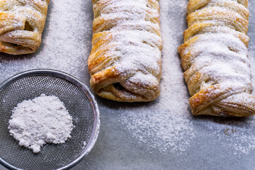 Delicious homemade cakes. Puff pastry with cherries, generously sprinkled with icing sugar on top. Delicious fresh buns close up view