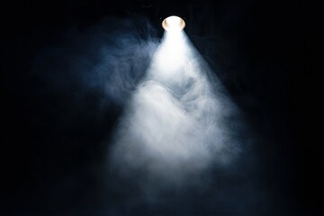 A dramatic spotlight piercing through a dense layer of smoke in a dark environment. This atmospheric scene is perfect for theater, mystery, or creative projects.