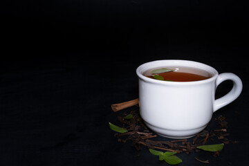 A cup of tea and tea leaves at black background