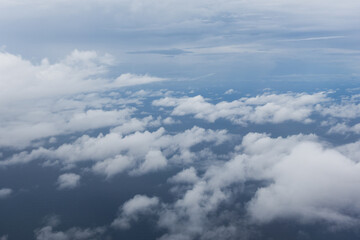 Fototapeta premium Cloudscape view from an airplane window on a sunny blue sky background. Skyline view, blue sky with clouds