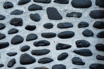 Pattern of river stones in cement. Floor gravel in garden. Stone wall background