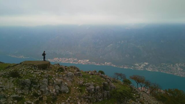 Man standing on a mountain above the Bay of Kotor drone view, Montenegro