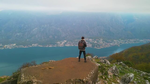 Man standing on a mountain above the Bay of Kotor drone view, Montenegro