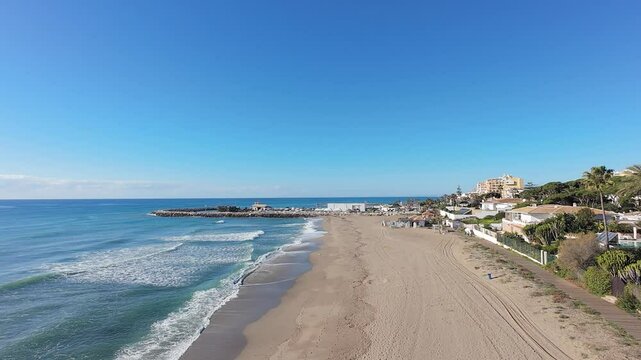 Aerial drone footage of the beautiful beach front in the Spanish town of Calahonda showing the Cabopino Marina in Marbella Spain and the Playa de Calahonda beach on a bright sunny day