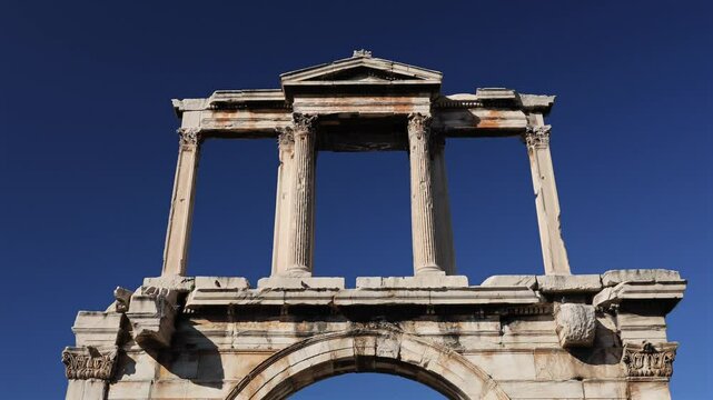 Arch of Hadrian with Acropolis Hill and Ancient World of Partheon in background. Wide angle 4k video with Arch of Hadrian during a sunny day in Athens with blue sky. History of Greece.