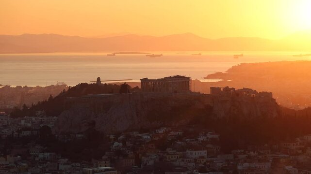 Sunset over Arcopolis hill in Athens. Beautiful orange sky landscape, view from above from Lycabetus Hill, to the Anciend World of Parthenon. Travel to Athens, Greece. 4k video