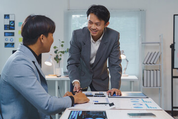 Two asian business people analyzing financial charts and digital tablet, discussing company strategy and planning for future projects in office meeting