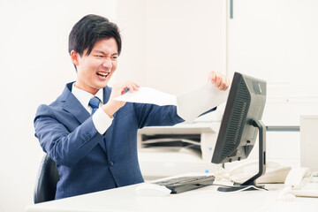 オフィスで書類を破り捨てるビジネスマン