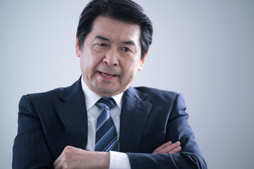 腕を組んで悩むシニアの経営者ビジネスマン　経営危機