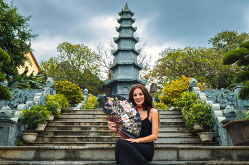 A female tourist on the background of the tower of the Buddhist temple in the Linh Un pagoda in Da...